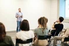 a man standing in front of a group of people while giving a presentation to them