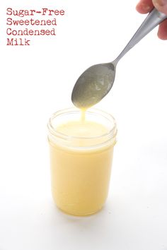 a hand holding a spoon over a jar filled with sugar - free sweetened milk