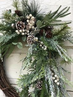 a wreath with pine cones and greenery is hanging on the side of a building