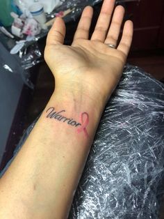 a woman's arm with a tattoo on it that reads, warrior and has a pink ribbon in the middle