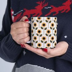 a woman holding a coffee mug with sunflowers on it