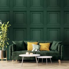 a living room with green walls and two tables in front of the couch is a potted plant