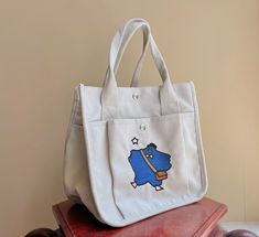 This unique tote bag is perfect for lunch bag or art supplies. It is embroidered with a design of a mailman duck.  There are two ways to use it: wear it across the body or hold it in your hand.  This cute bag has two magnetic closures and side pockets.  The dimensions are 9 * 8.5 * 5 inches Large Capacity Satchel Lunch Bag For School, Large Capacity Canvas Lunch Bag For Daily Use, Large Capacity Shoulder Lunch Bag For School, School Shoulder Lunch Bag With Large Capacity, School Lunch Bag With Large Capacity, Cute Tote Lunch Bag For School, Cute School Tote Lunch Bag, Cute Large Capacity Lunch Bag, Cute Large Capacity Lunch Bag For Everyday