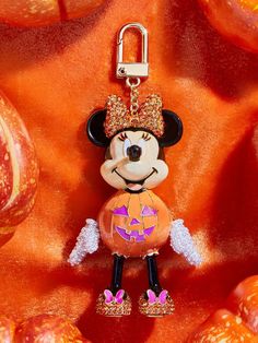 a mickey mouse keychain hanging on an orange fabric with pumpkins in the background