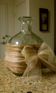 a glass bottle wrapped in twine and tied with a bow on a counter top