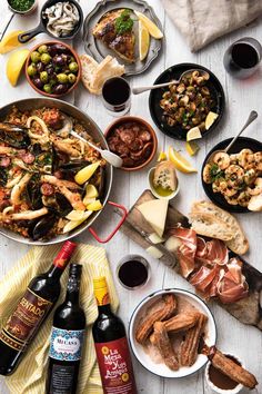 a table topped with lots of different types of food and wine next to bottles of wine