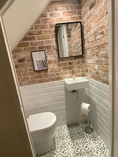 a bathroom with a toilet, sink and brick wall in it's doorway way