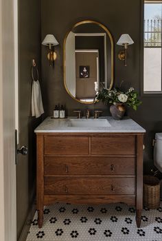 a bathroom with a sink, mirror and lights on the wall next to a toilet