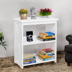 a white book shelf with books and flowers on top