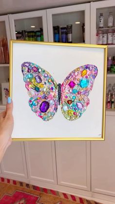 a person holding up a colorful butterfly painting