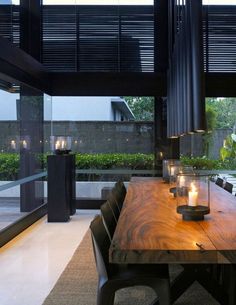 a wooden table with candles on it in front of a large glass window that looks out onto the backyard