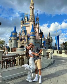 a man and woman pose for a photo in front of the castle at disney world