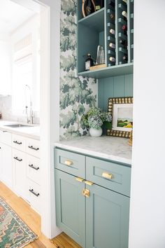 a kitchen with blue cabinets and white counter tops, along with green wallpaper on the walls