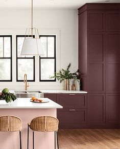 a kitchen with purple cabinets and white counter tops, two chairs in front of the island