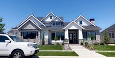 a white suv is parked in front of a house with stone and shingles on it