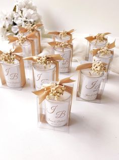 wedding favors in clear boxes with gold ribbons and bows on them are ready for the guests to arrive