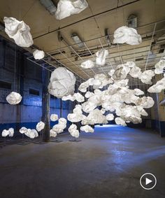 a room with lots of white paper balls hanging from the ceiling and suspended by wires