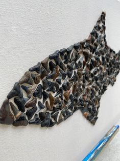 a piece of art that looks like a fish made out of rocks on a wall