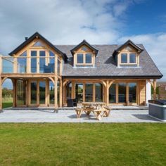 a large wooden house sitting on top of a lush green field next to a picnic table