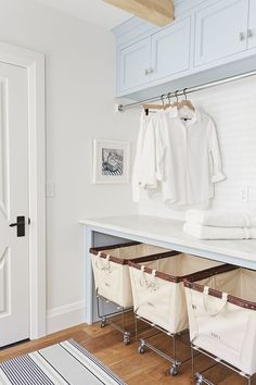 an organized closet with clothes hanging on hooks and storage bins under the counter top