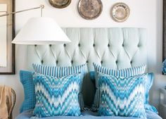 a bedroom with blue and white bedding, plates hanging on the wall above it