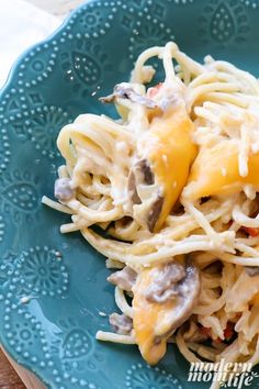 a blue plate topped with pasta covered in cheese and mushrooms on top of a wooden table