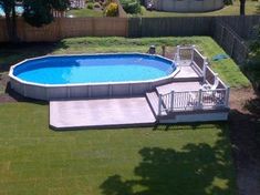 an above ground swimming pool surrounded by grass and fenced in area with stairs leading up to it