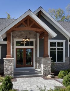 the front entrance to a house with stone pillars and columns on each side, surrounded by greenery