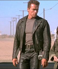 a man and woman are walking down the street in leather outfits, one is wearing a gray t - shirt