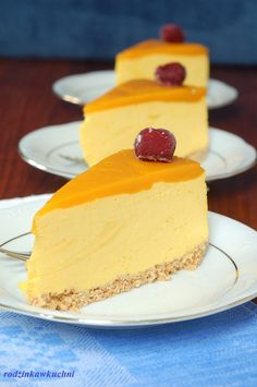 three slices of cheesecake on white plates with cherries and cranberry toppings