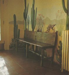 a wooden bench sitting in front of a wall with cacti and plants on it