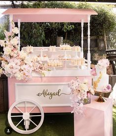 a pink and white dessert cart with cupcakes on the top is decorated with flowers