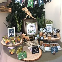 a dinosaur themed birthday party with cupcakes and desserts on the side table