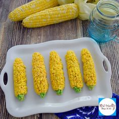 rice krispies corn on the cob is sitting on a plate next to some corn