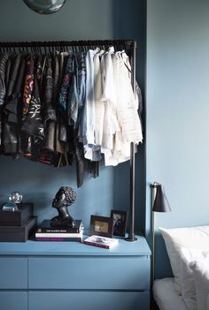 a blue dresser with clothes hanging on it