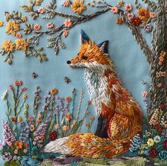 a fox sitting in the grass next to a tree with lots of flowers on it