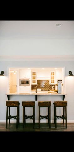 three stools sit in front of a kitchen island with an oven and microwave on it