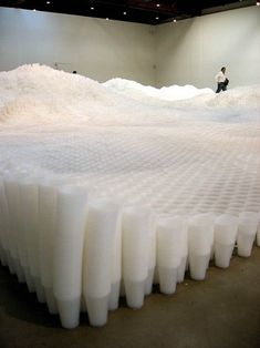 a large pile of white plastic material in a room with a man standing next to it