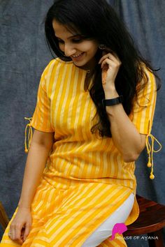 a woman sitting on a chair talking on her cell phone while wearing a yellow and white striped dress