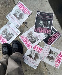 several newspaper articles laying on the ground next to someone's feet and black shoes