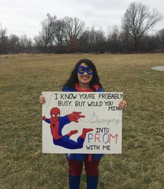 a girl dressed as spiderman holding up a sign