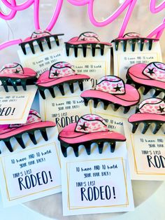 some pink and black hair combs are on a white plate with tags that say rodeo