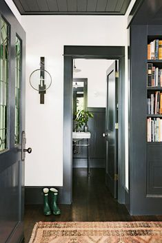 an entryway with bookshelves, rug and green boot boots on the floor