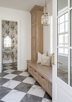 a hallway with a checkered floor and wooden cabinets in the corner, next to a white door