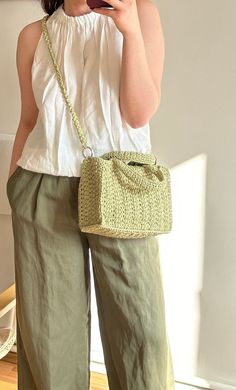 a woman is taking a selfie with her cell phone while wearing green pants and a white top