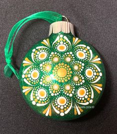 a green ornament with white and yellow designs on it's side sitting on a gray surface