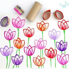 some flowers are drawn on a piece of paper with tape next to them and two rolls of toilet paper