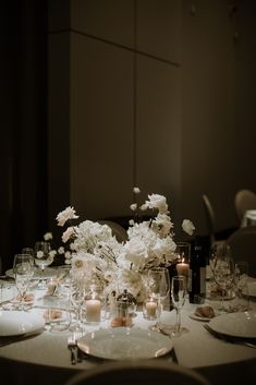 the table is set with white flowers and candles for an elegant dinner or reception party