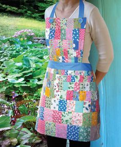 a woman wearing an apron made out of patchwork fabric and holding her hands on her hips