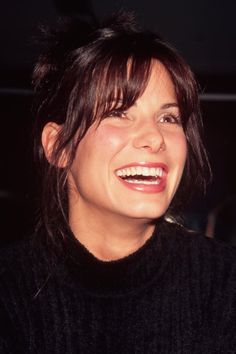 a woman smiling and wearing a black sweater